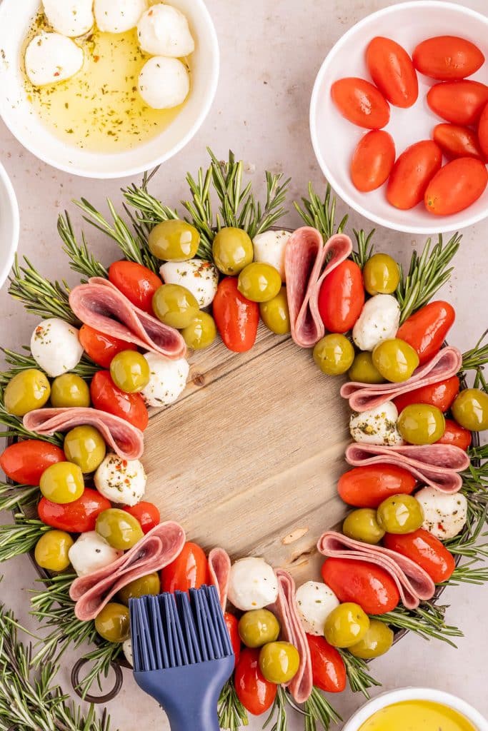 pastry brush brushing oil onto an antipasto wreath.