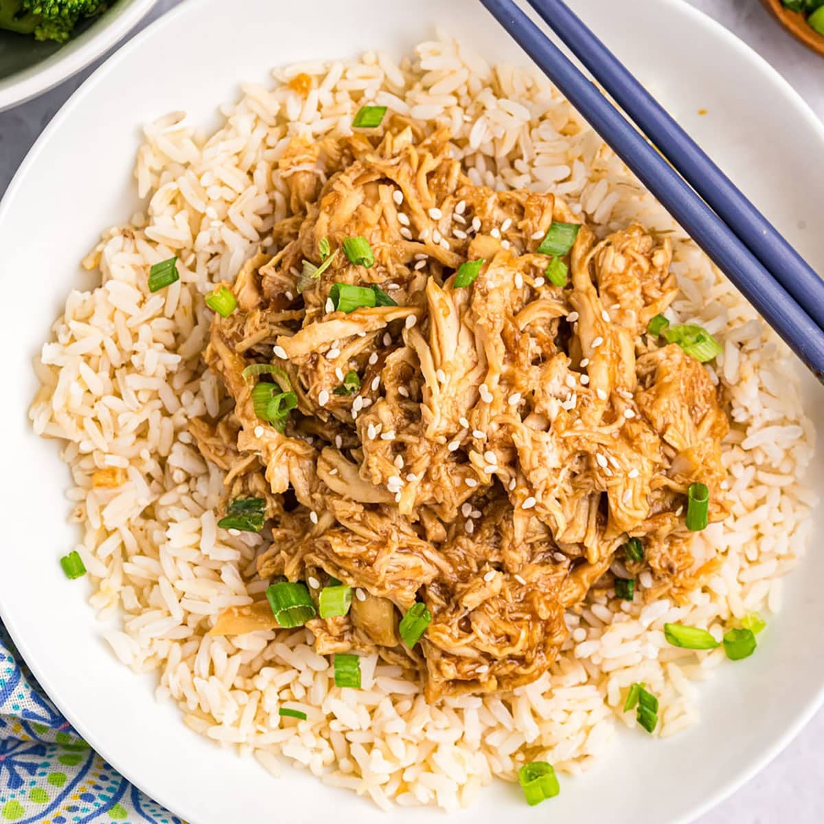 overhead shot of teriyaki chicken on a bed of rice with chopsticks.