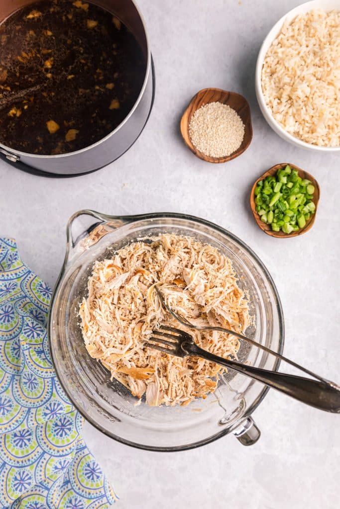 overhead shot of shredded chicken in a glass bowl.