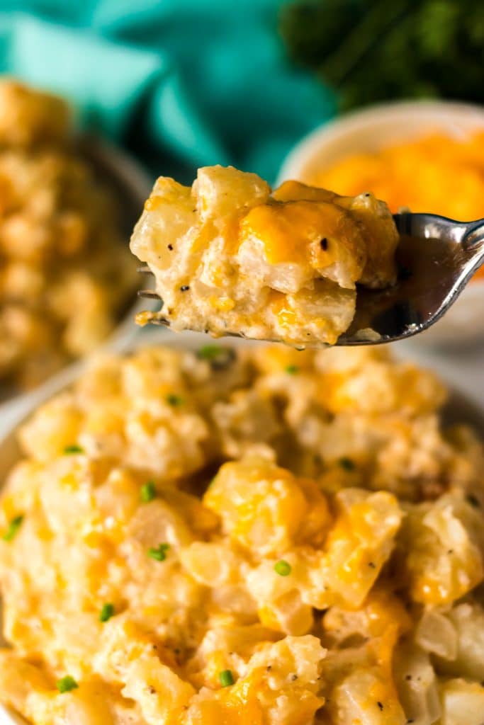 fork lifting a bite of cheesy potatoes from a plate.