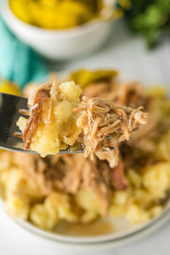 fork lifting a bite of mississippi chicken and mashed potatoes.