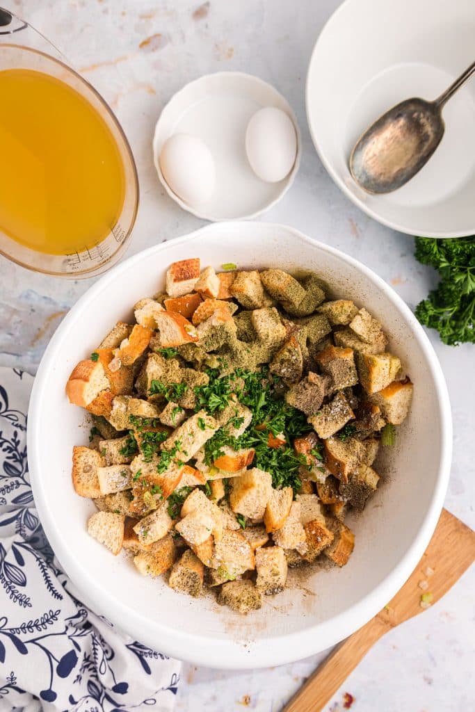 overhead shot of cubes of bread and herbs in a mixing bowl.