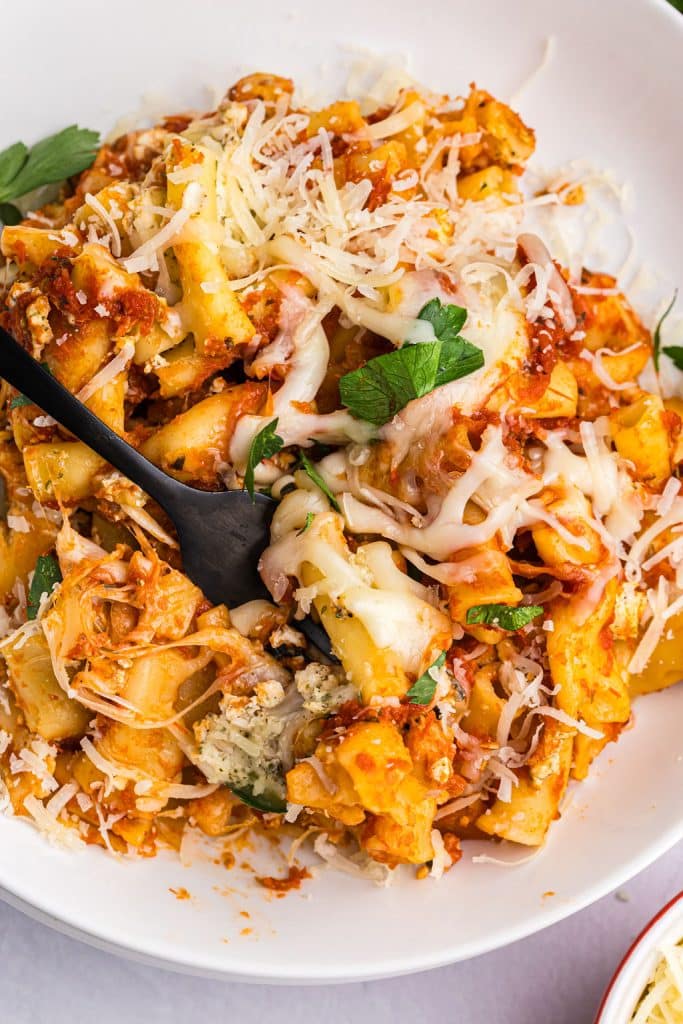 fork lifting a bite of ziti from a plate.