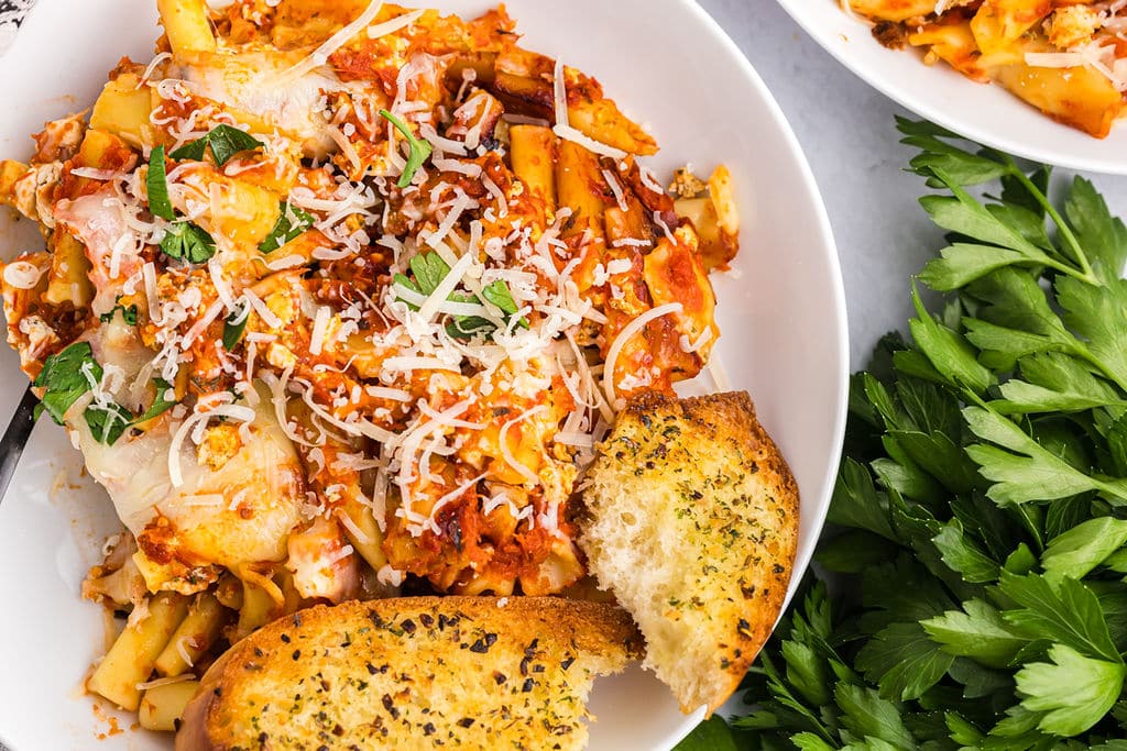 ziti and garlic bread on a white plate.