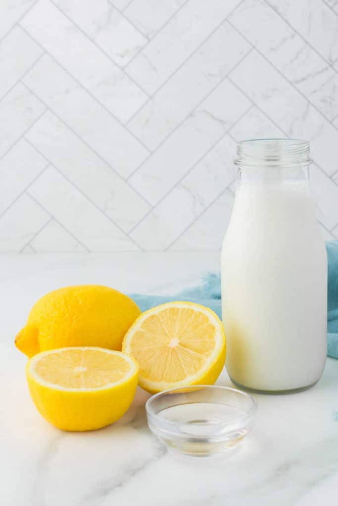 glass bottle of buttermilk next to lemons.