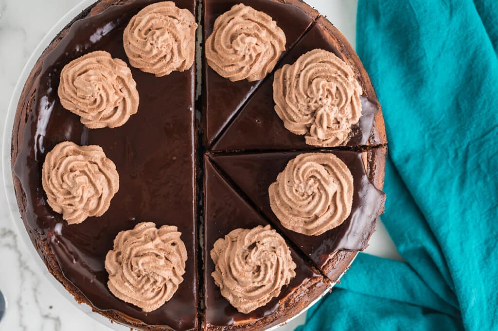 overhead shot of chocolate whipped cream piped onto a chocolate cheesecake.