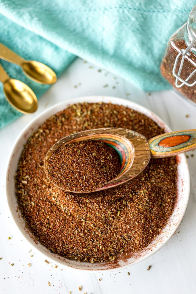 plate of chili seasoning with a wooden scoop.