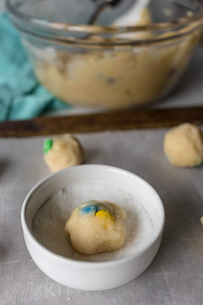 ball of dough in a small dish of granulated sugar.
