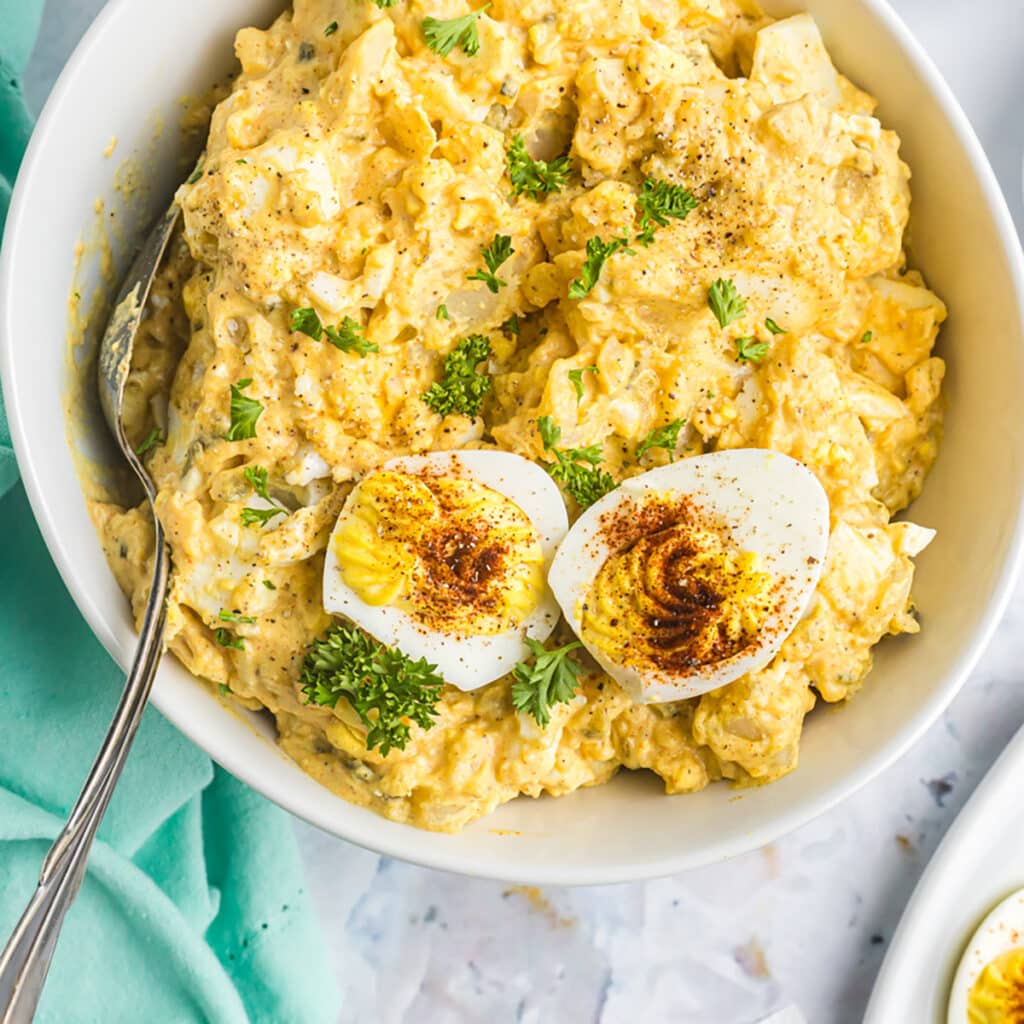 bowl of deviled egg potato salad topped with a deviled egg.