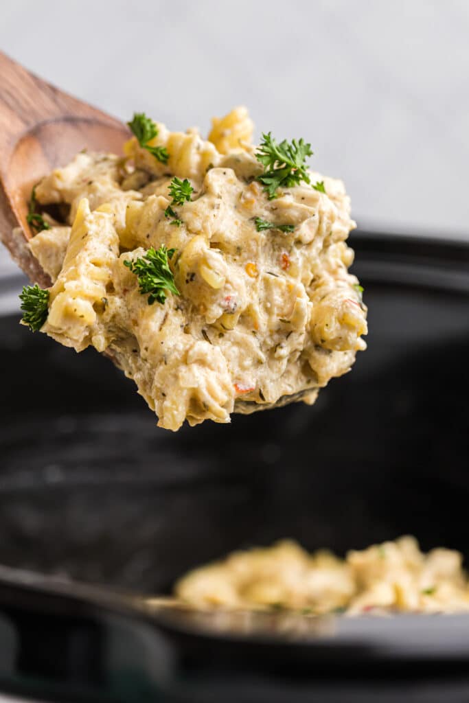 spoon lifting a scoop of chicken pasta from a crockpot.