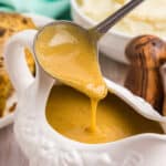 ladle scooping chicken gravy from a gravy boat.