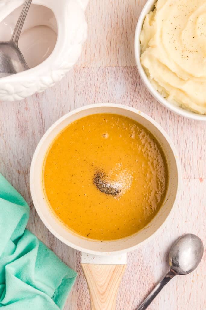 salt and pepper seasoning a pan of gravy.