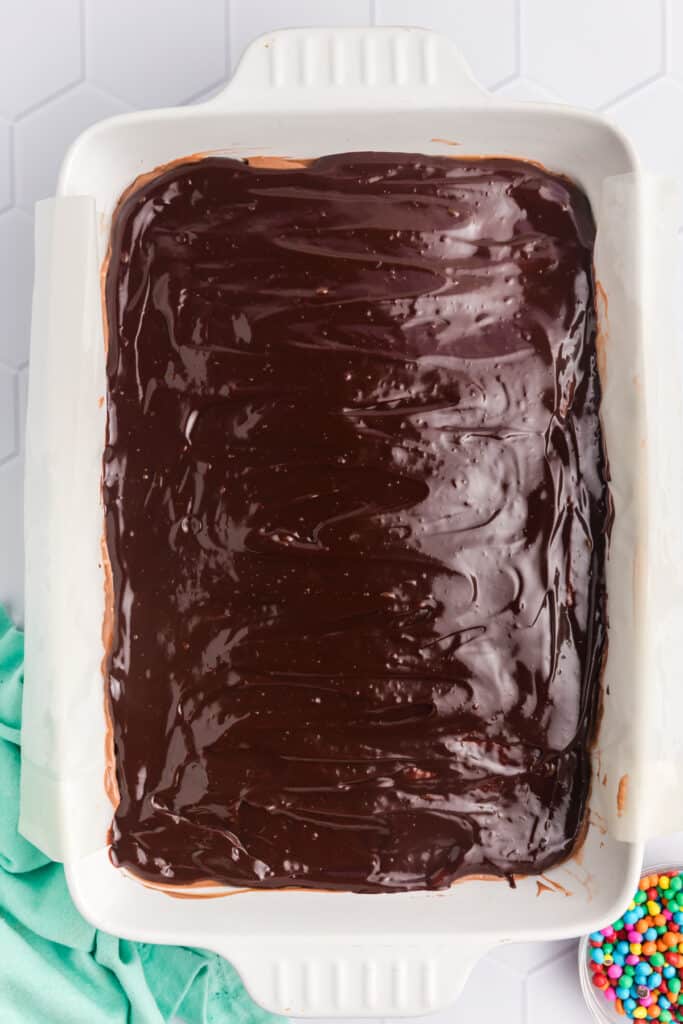 overhead shot of ganache spread over brownies in a baking dish.