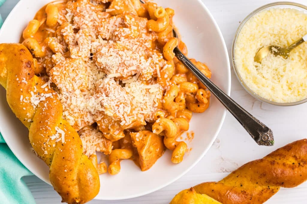 plate of creamy chicken pasta with a breadstick.