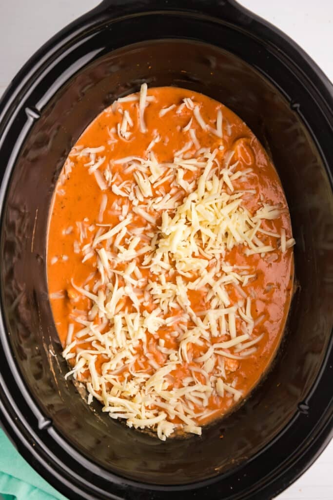 shredded mozzarella sprinkled in a crockpot.
