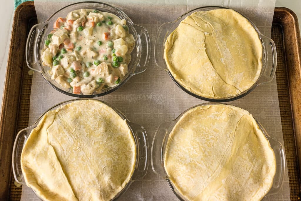 four pot pies; three topped with crust, before baking.
