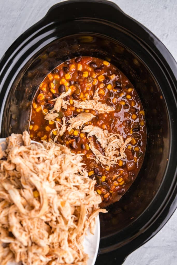 shredded chicken pouring into a crockpot.