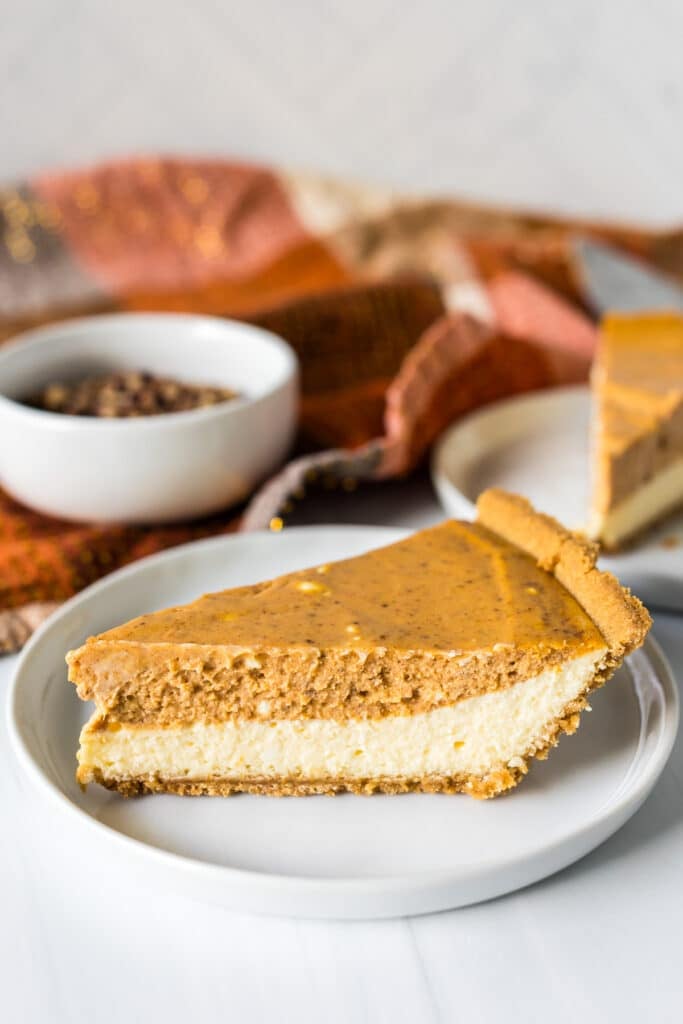 slice of layered pumpkin cheesecake on a white plate.