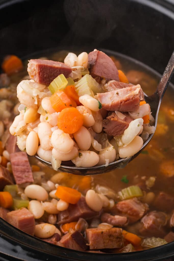 ladle lifting a scoop of ham bean soup from a crockpot.