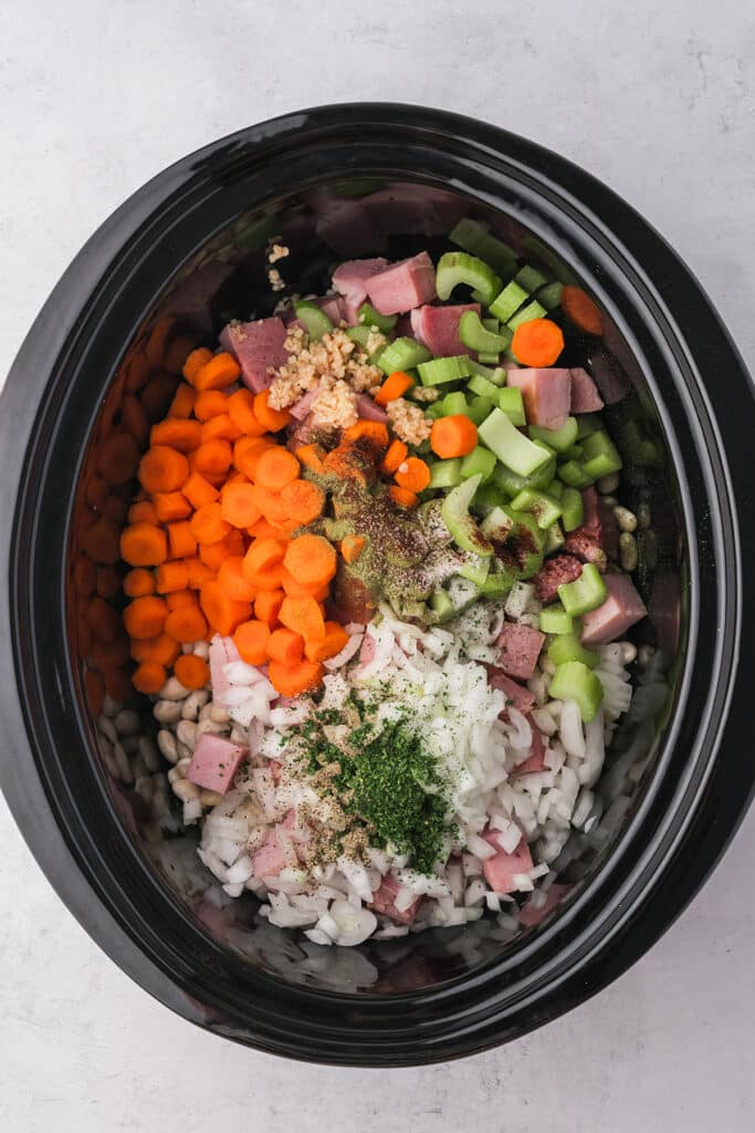 overhead shot of diced veggies, ham & beans in a crockpot.