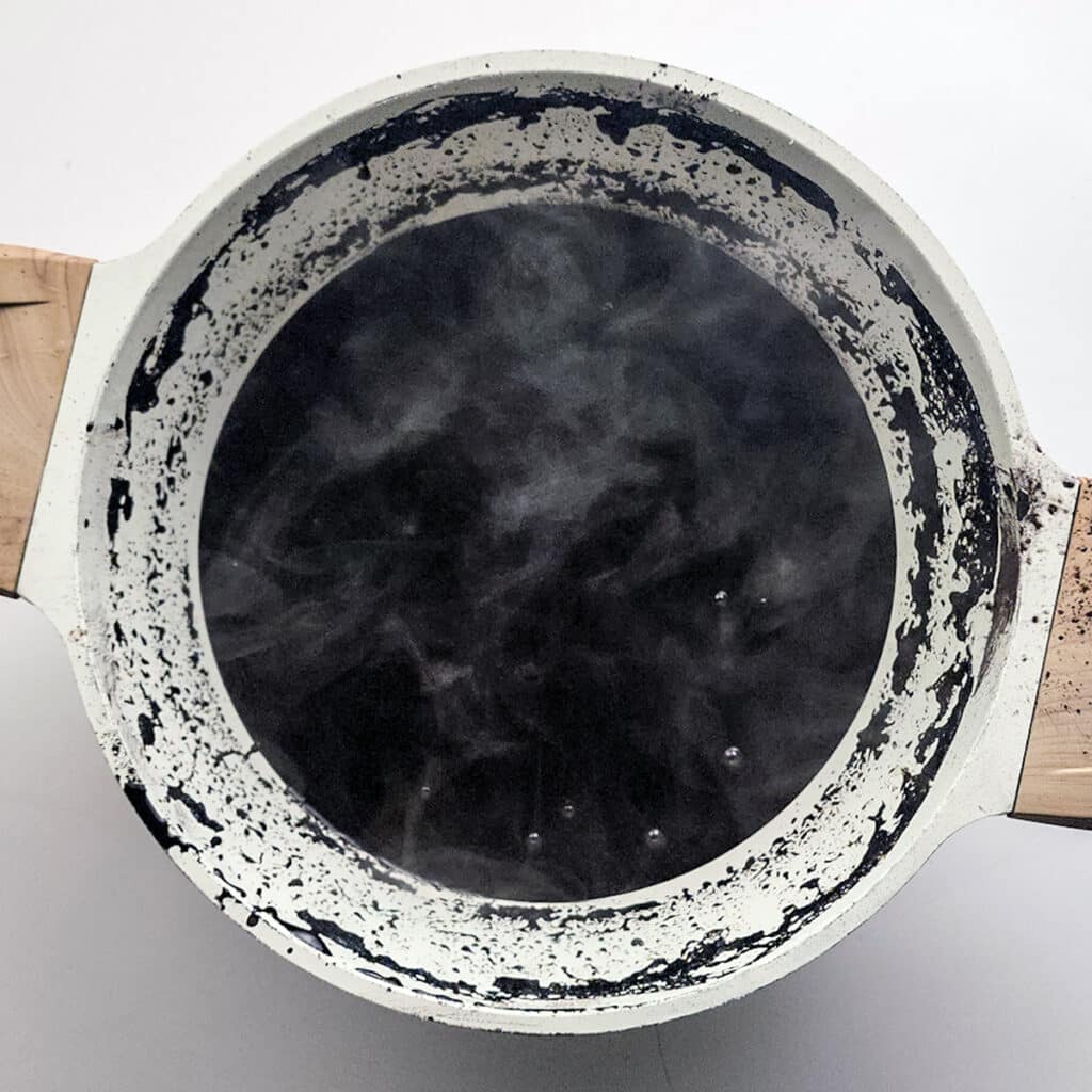overhead shot of steaming black hot cocoa in a pot.