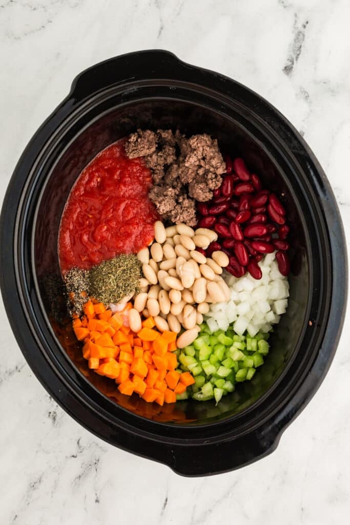 overhead shot of vegetables in a crockpot to make soup,