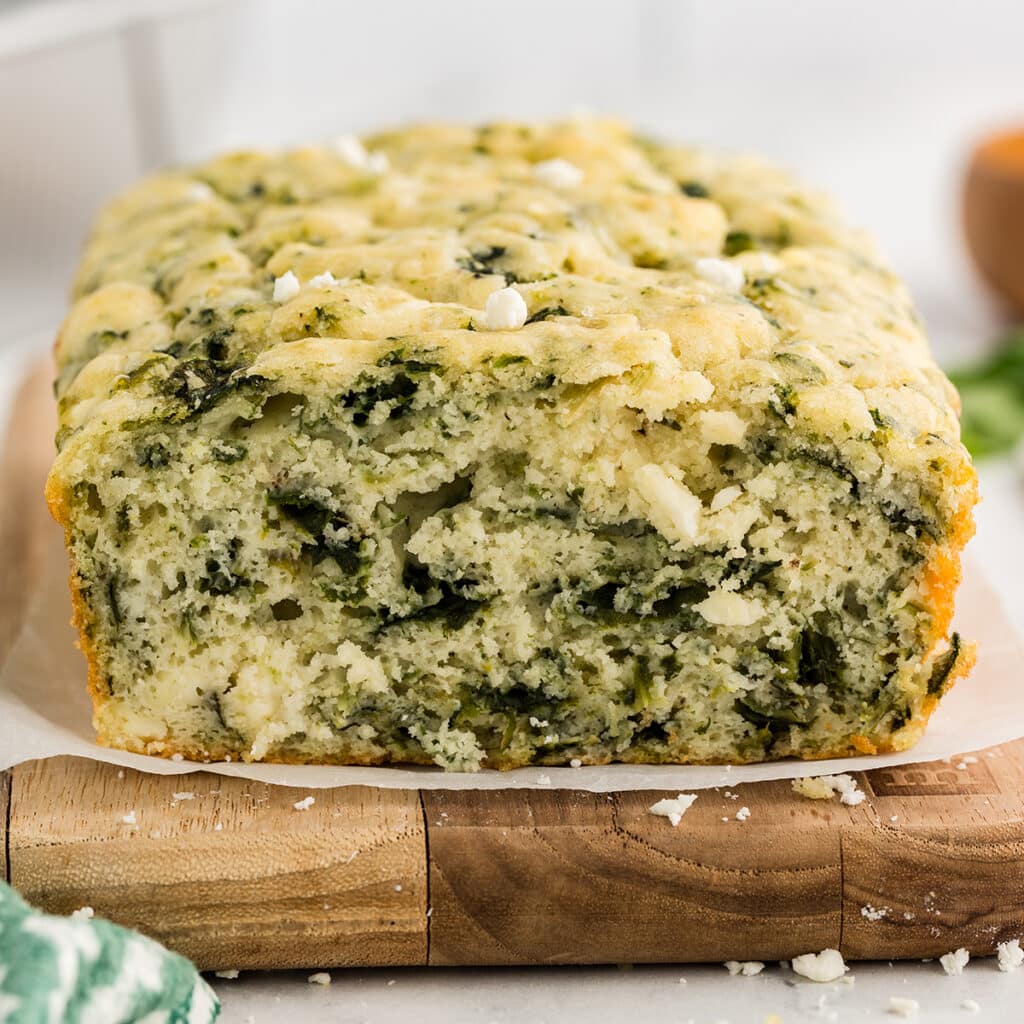 loaf of spinach feta bread on a wood board.