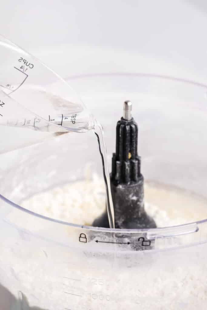water drizzling into a food processor.