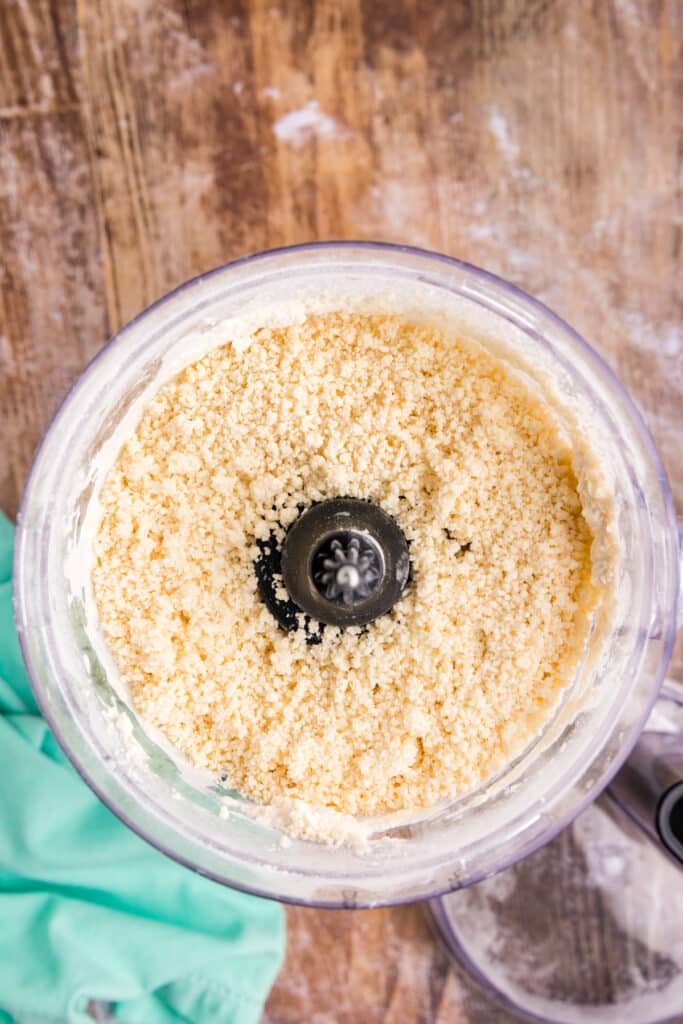 overhead shot of crumbly pie dough in a food processor.