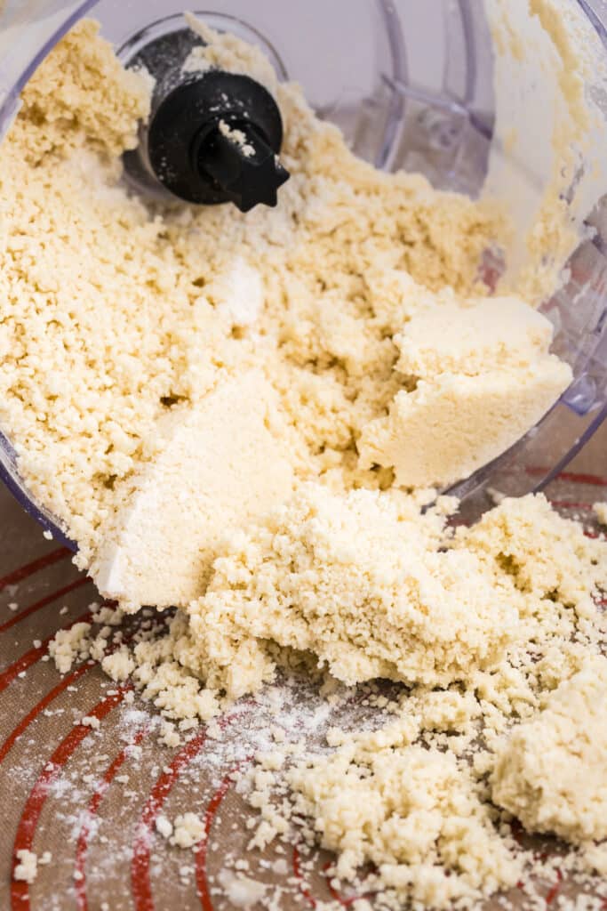crumbly pie dough pouring out of a food processor.