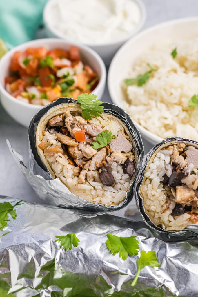 carnitas burrito wrapped in foil and cut in half.