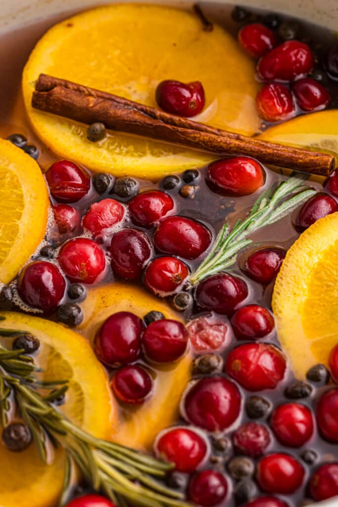 closeup of cranberries, oranges, and rosemary in a simmer pot.