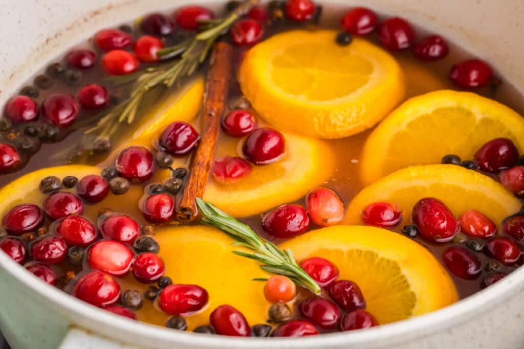 closeup of cranberries, oranges, and rosemary in a potpourri pot.