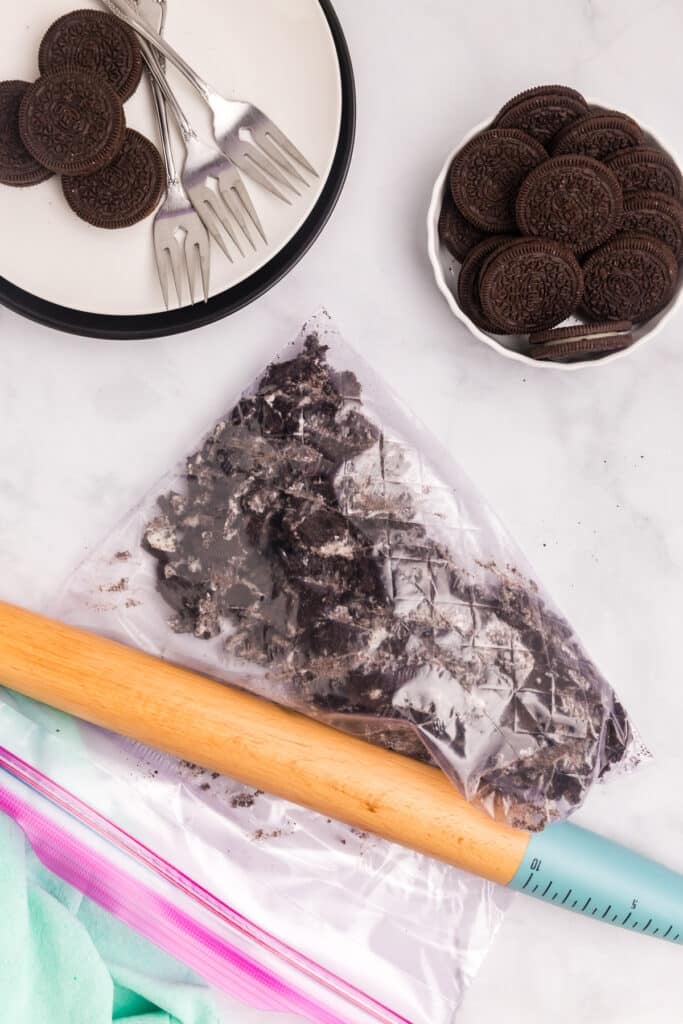 Crushed cookies in a plastic bag with a rolling pin.