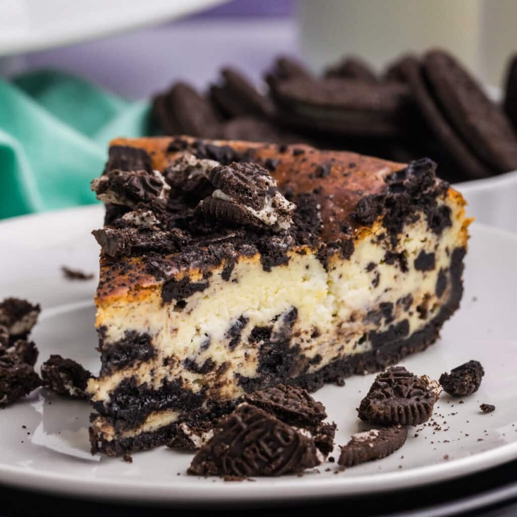 A slice of cookies and cream cheesecake topped with crushed cookies.