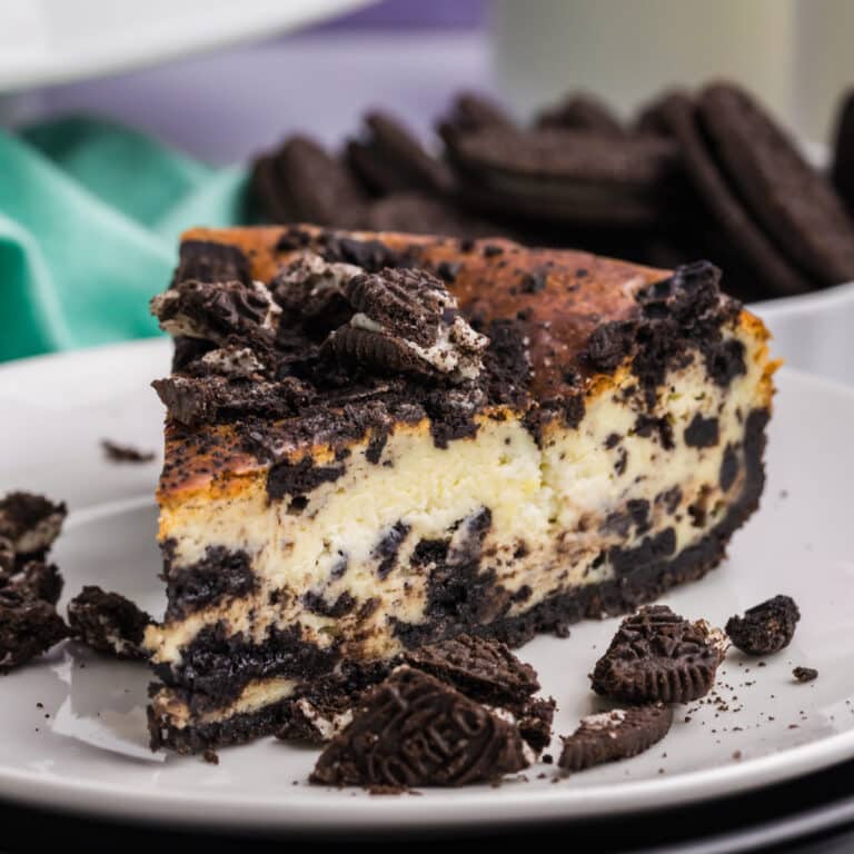 A slice of cookies and cream cheesecake topped with crushed cookies.