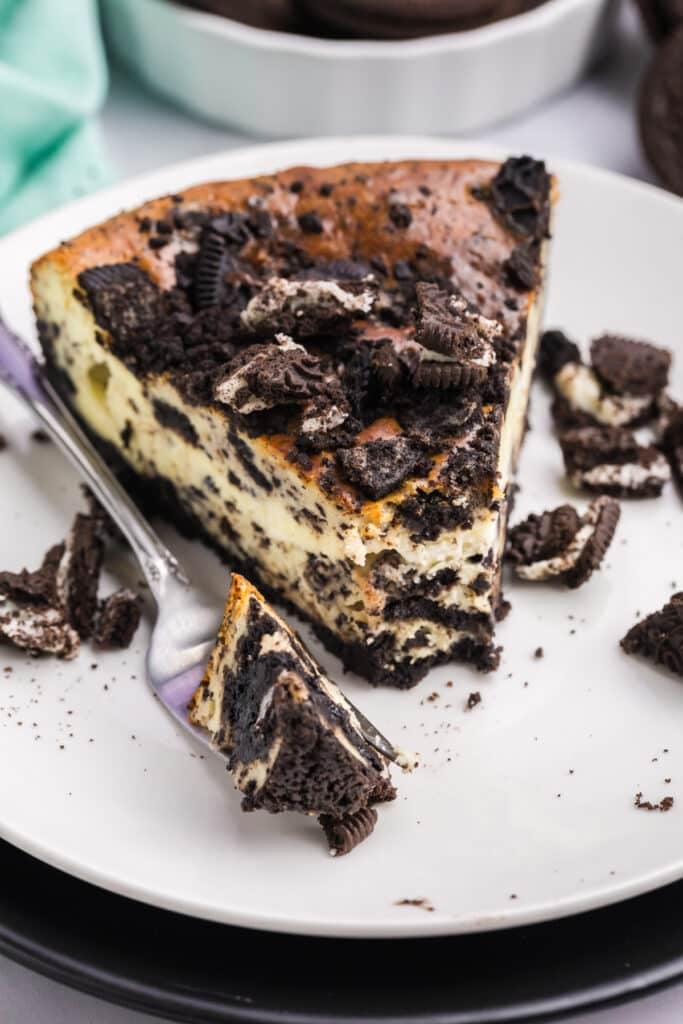 A slice of cookies and cream cheesecake with a bite taken out.
