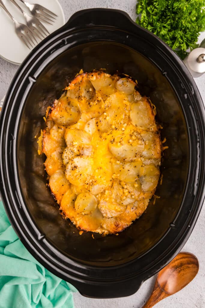 Crockpot scalloped potatoes topped with cheese and herbs.