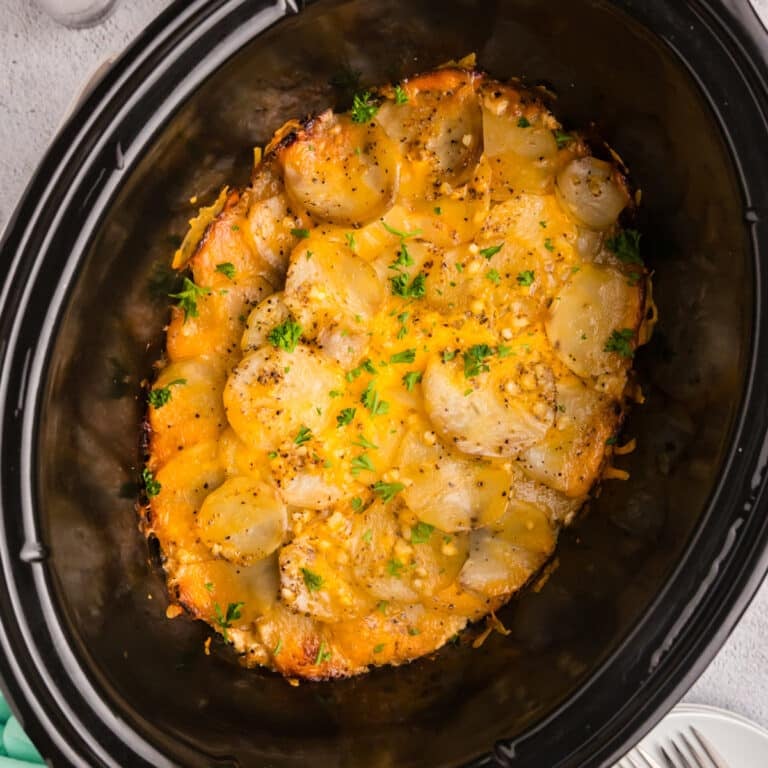 Crockpot scalloped potatoes topped with cheese and herbs.