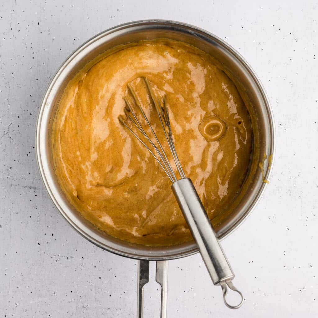 Thick caramel mixture being stirred in a saucepan.