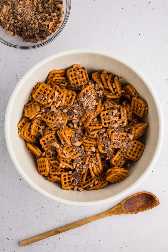 Bowl of pretzels topped with toffee and chocolate bits.