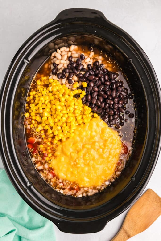 overhead shot of corn, black beans, and creamed corn in a crockpot.