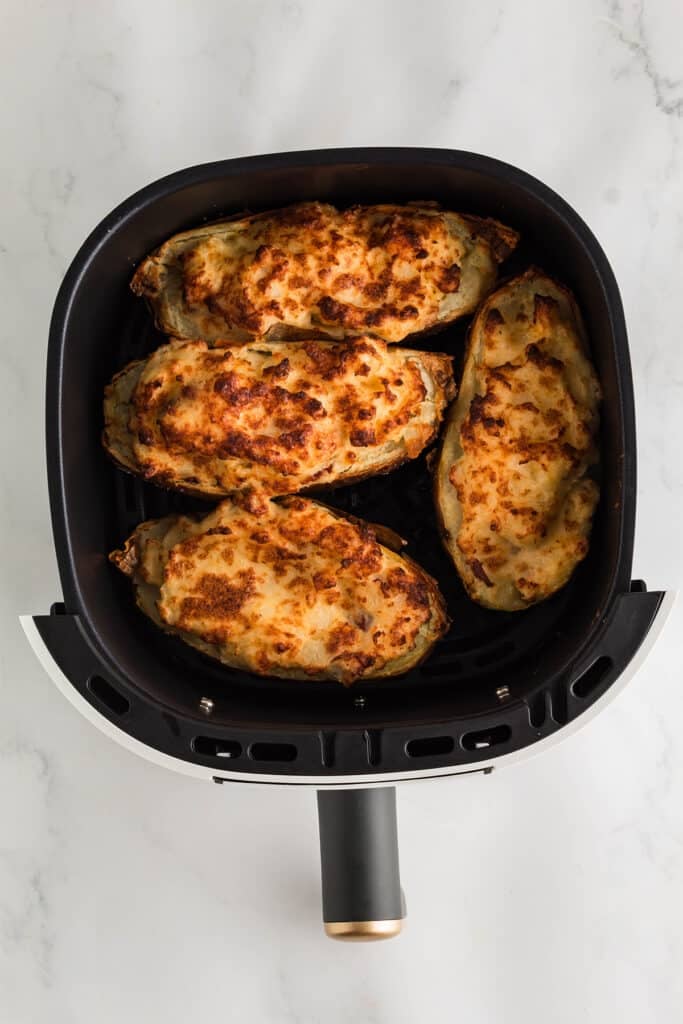 overhead shot of twice baked potatoes in an air fryer basket.