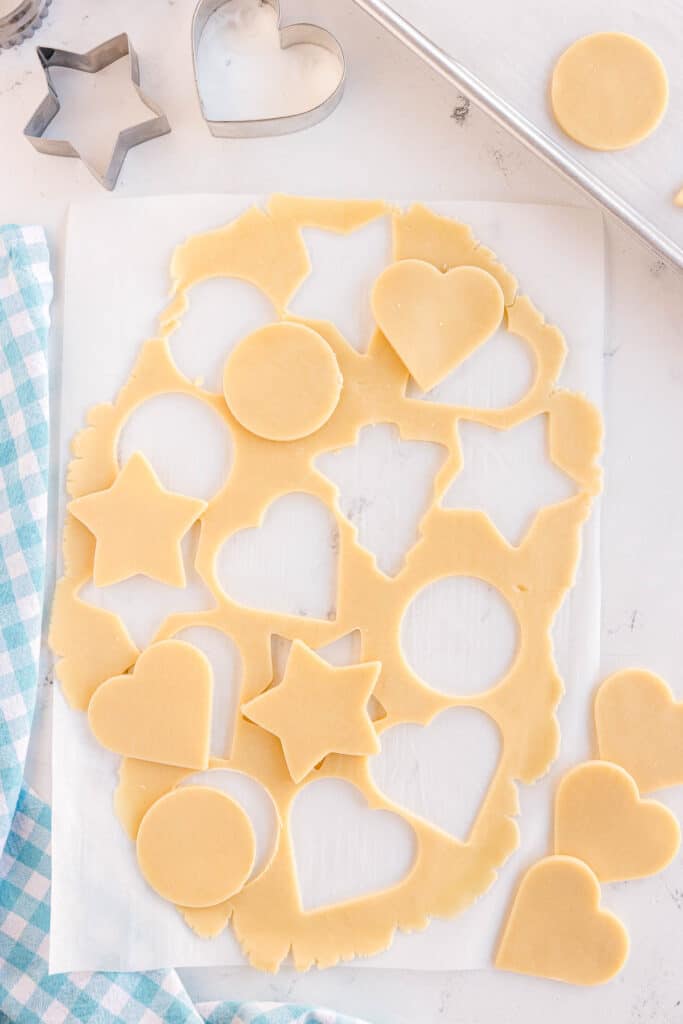 A rolling pin pressing cookie dough between parchment paper.