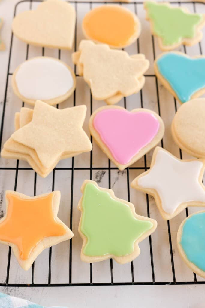 colorful iced and plain sugar cookies on a cooling rack.