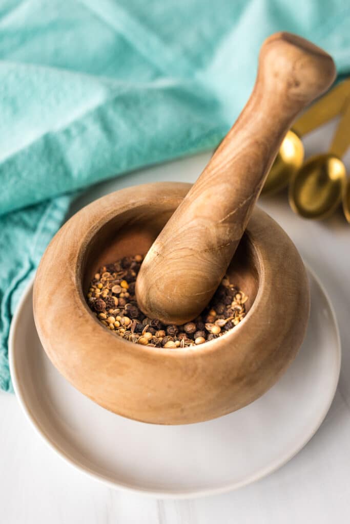 a wooden mortar & pestle with seasonings in it.