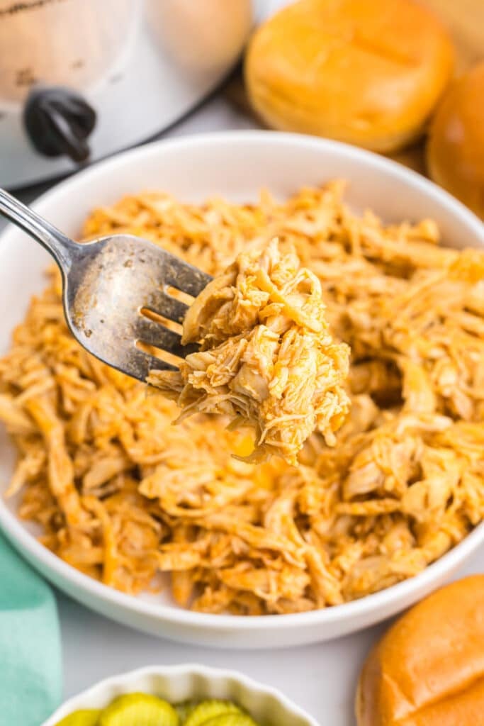 fork lifting shredded nashville hot chicken from a platter.