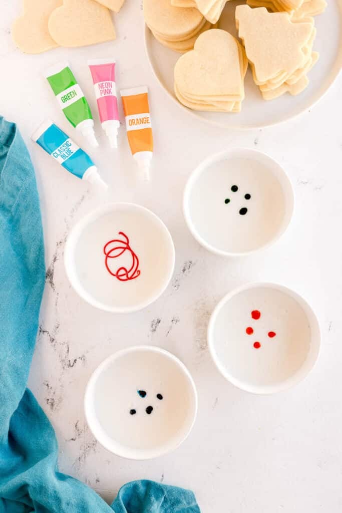 Bowls of icing with food coloring drops.