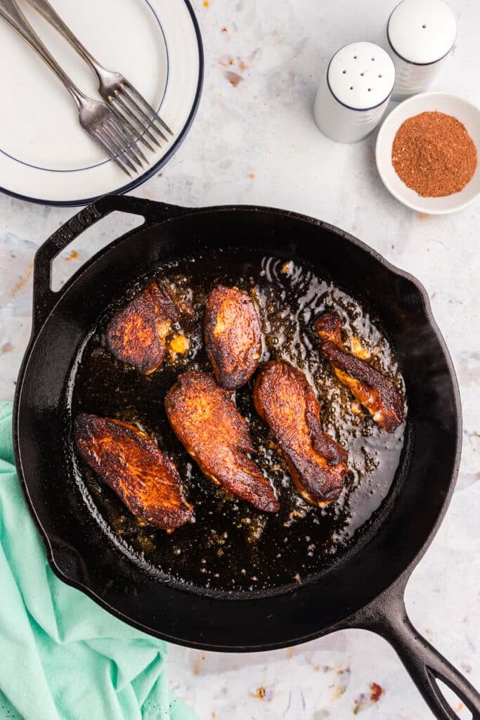 Blackened chicken tenders cooking in a cast iron skillet.