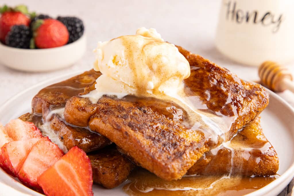 French toast topped with a scoop of vanilla ice cream and honey syrup.